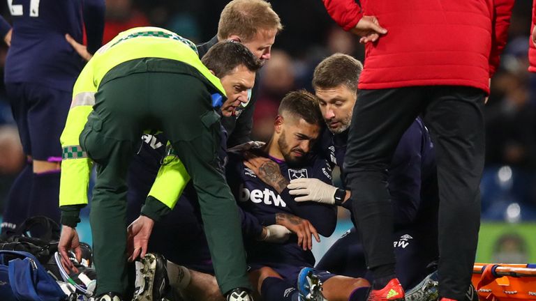 Lanzini holds his shoulder as he receives medical treatment on the pitch at Turf Moor